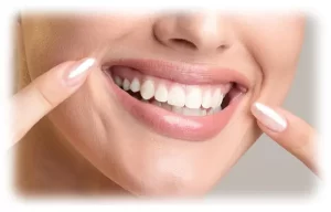 A woman pointing to her whitenend teeth.